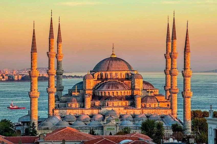 Une grande mosquée dotée de plusieurs minarets et de coupoles, entourée d’eau et avec une vue sur la ville en arrière-plan. 1
