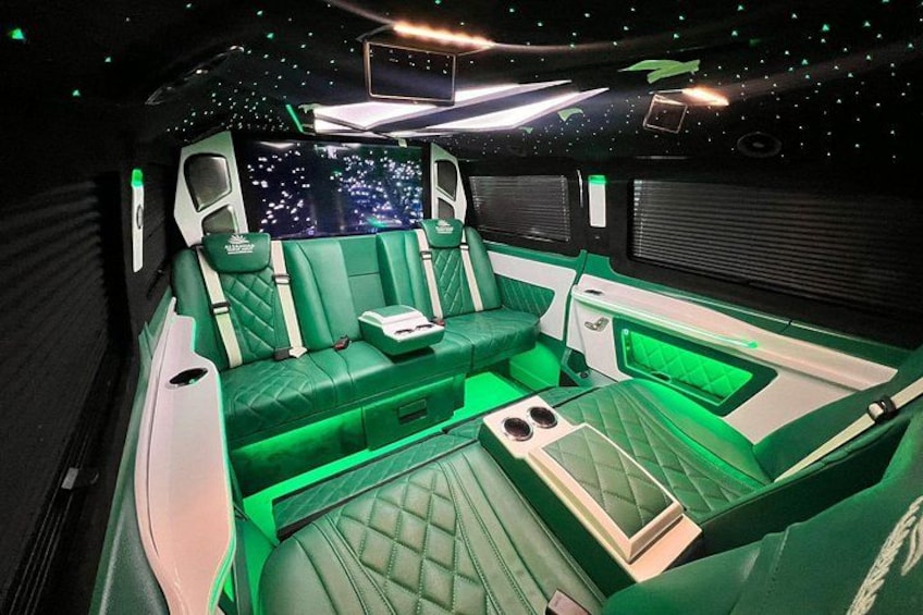 Un habitacle luxueux avec un revêtement vert, une console centrale et un affichage représentant un ciel étoilé. 3