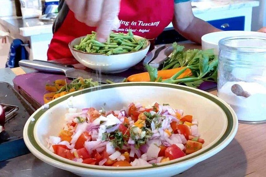 Una persona preparando una ensalada con diversas verduras en una cocina. 3