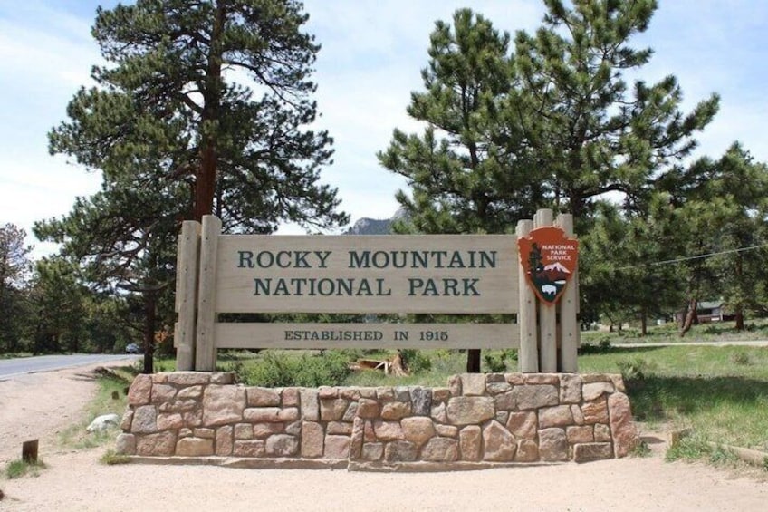 A sign for Rocky Mountain National Park with a stone base and a logo. 5