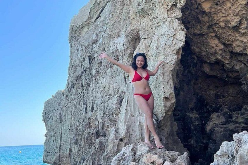 A person in a red bikini standing on a rocky cliff by the sea. 3