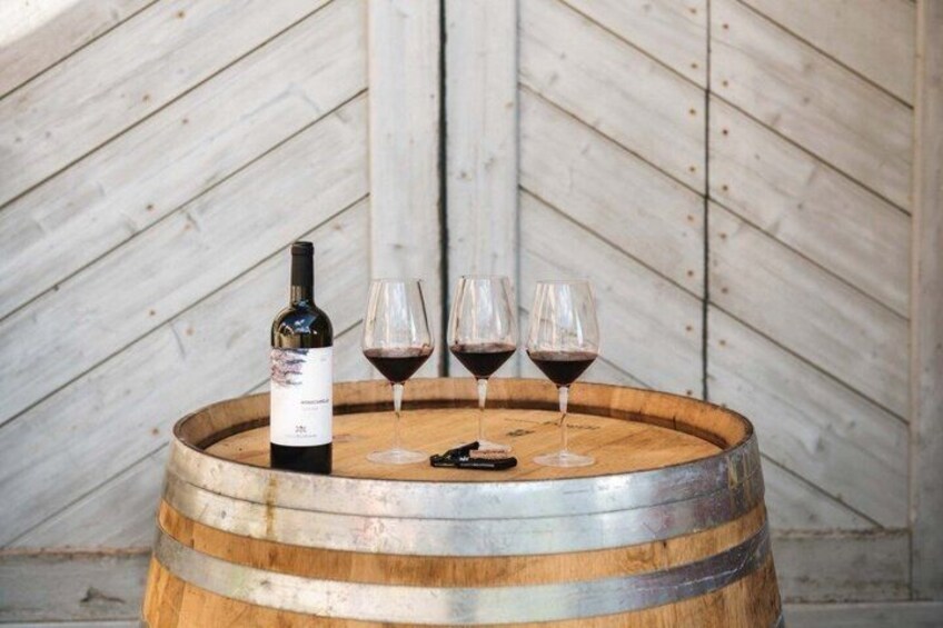 A wooden barrel with a wine bottle and three glasses of red wine. 2
