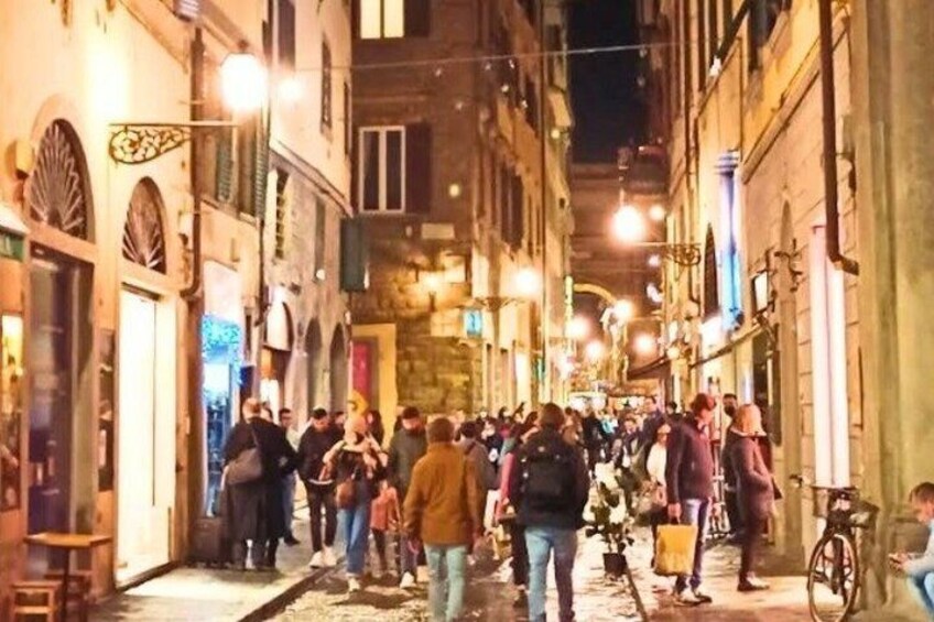 A crowded street at night with people walking and bicycles parked along the sides. 2