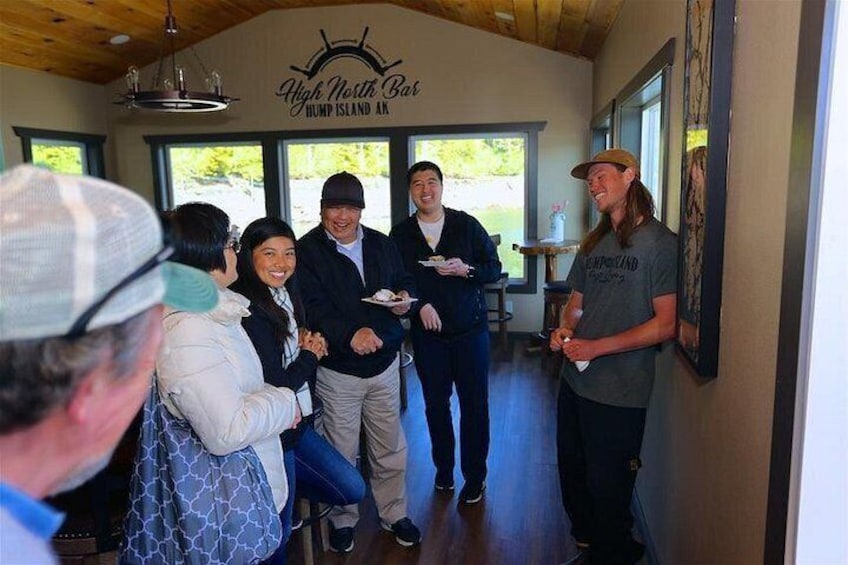A group of people inside a building with a sign reading 'High North Bar' and 'Hump Island AK'. 2