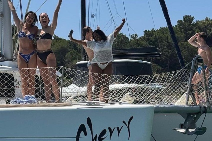 Un gruppo di persone su una barca con ringhiera a rete, cielo sereno e alberi sullo sfondo. 5