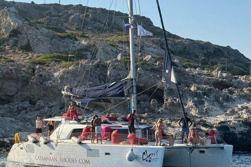 A white boat with people on board, sailing near rocky cliffs. 3
