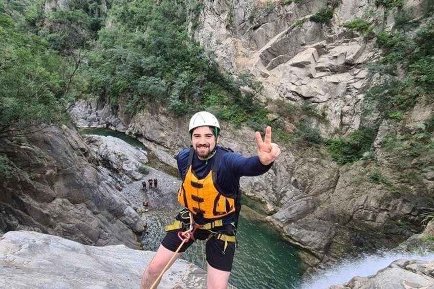 A person rappelling down a rocky cliff with a river below. 4