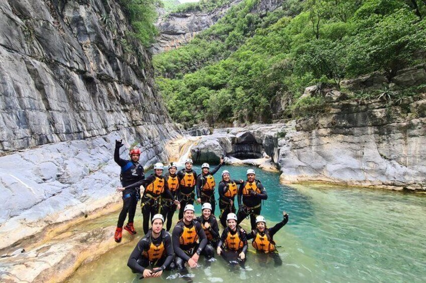 A group of people in a canyon with clear water and rocky cliffs. 1