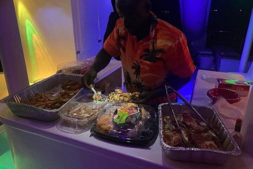 A buffet table with various food items and a person serving food. 3