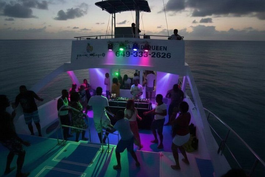 A boat with people dancing and a DJ booth. 1