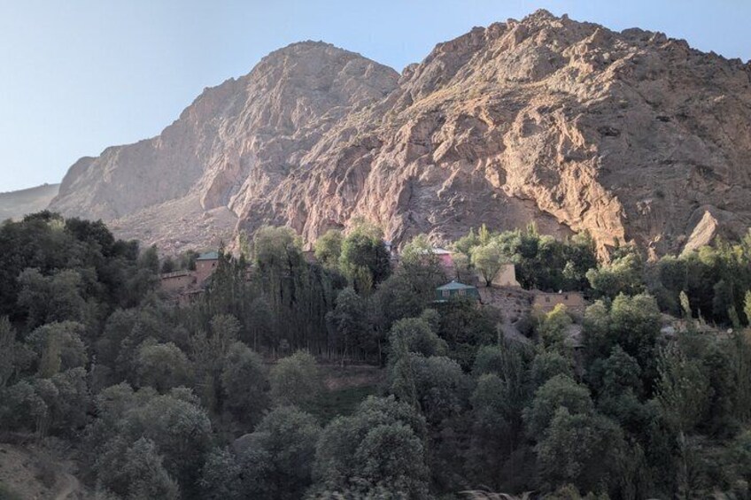 Un paisaje montañoso con un bosque denso en primer plano y una montaña rocosa al fondo. 2