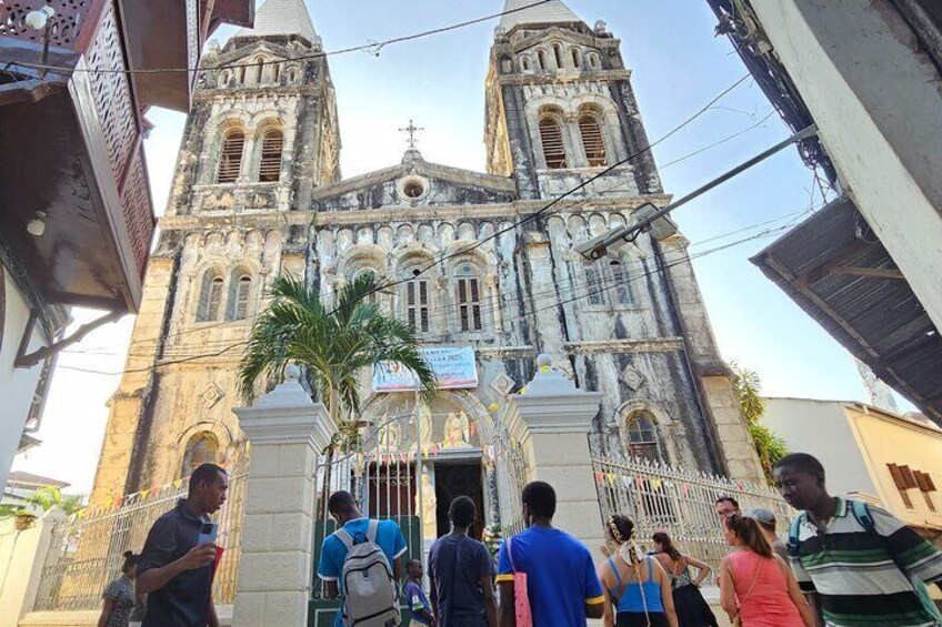 A historic church with two towers and a central dome, surrounded by a fence and palm trees. 1