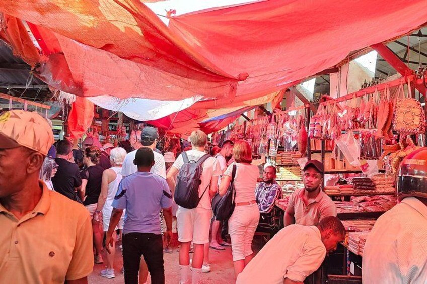 Un mercado concurrido, con gente mirando y comprando bajo toldos rojos. 4