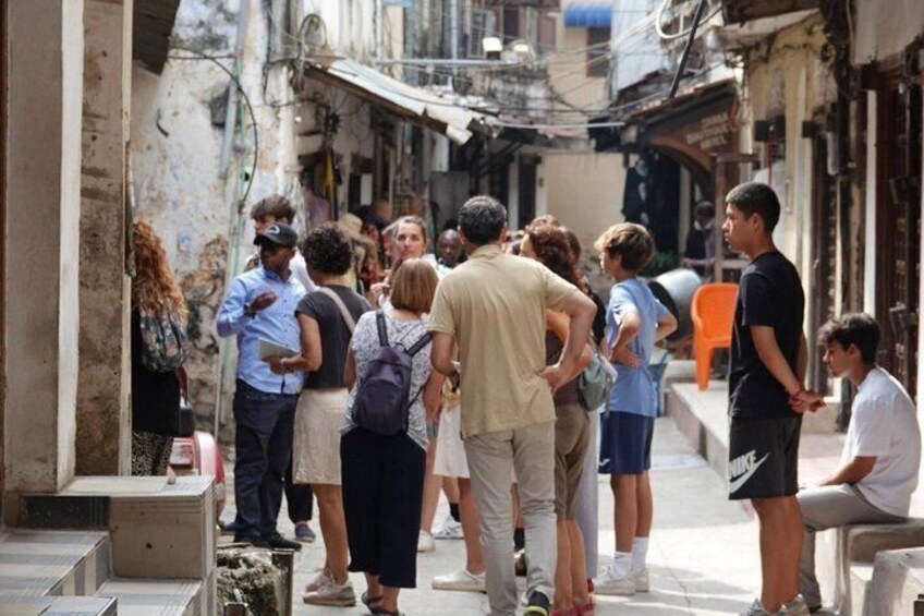 A group of people standing in an urban alleyway with buildings on either side. 5