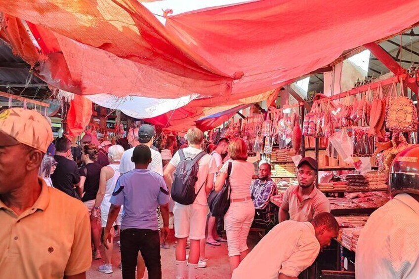 A crowded market with people browsing and vendors selling goods under red canopies. 4