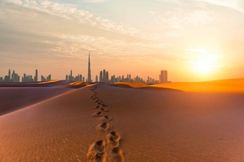 A desert landscape with a city skyline in the background and a trail of footprints leading towards the city. 1