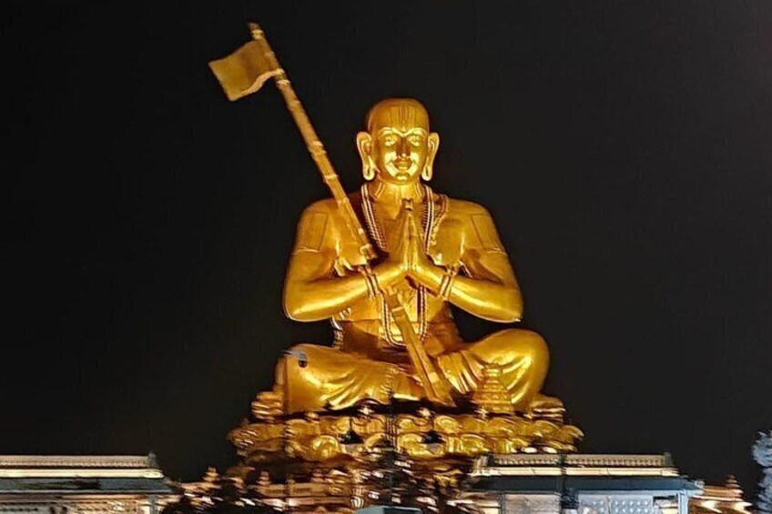 En stor gylden statue af en siddende figur, der holder et flag, med detaljeret udformning og en fod 3