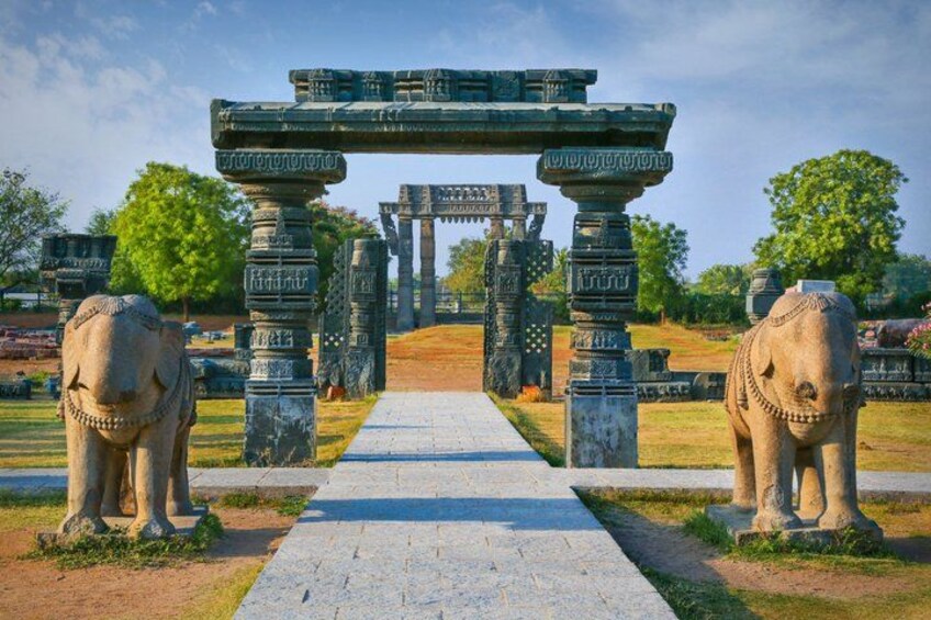 An ancient stone archway with two elephant statues on either side, leading to a temple complex. 5