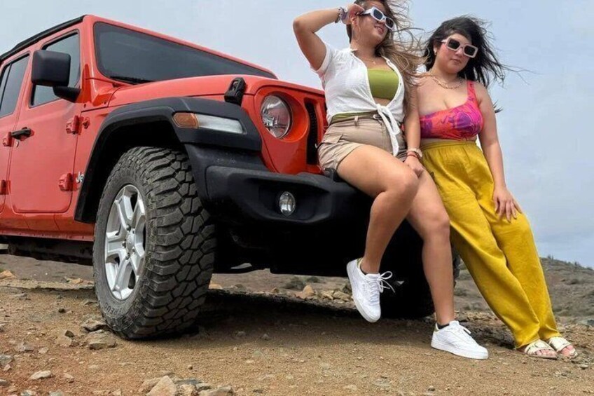 Due persone che posano accanto a un fuoristrada rosso su un terreno roccioso. 2