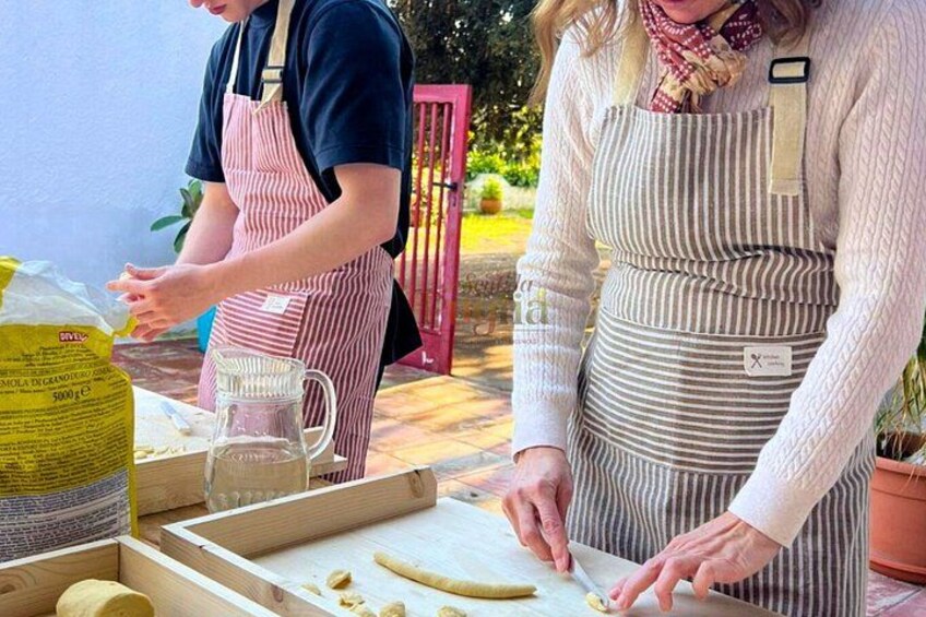 Due persone preparano cibo all'aperto, una taglia verdure e l'altra maneggia un sacco di farina. 5