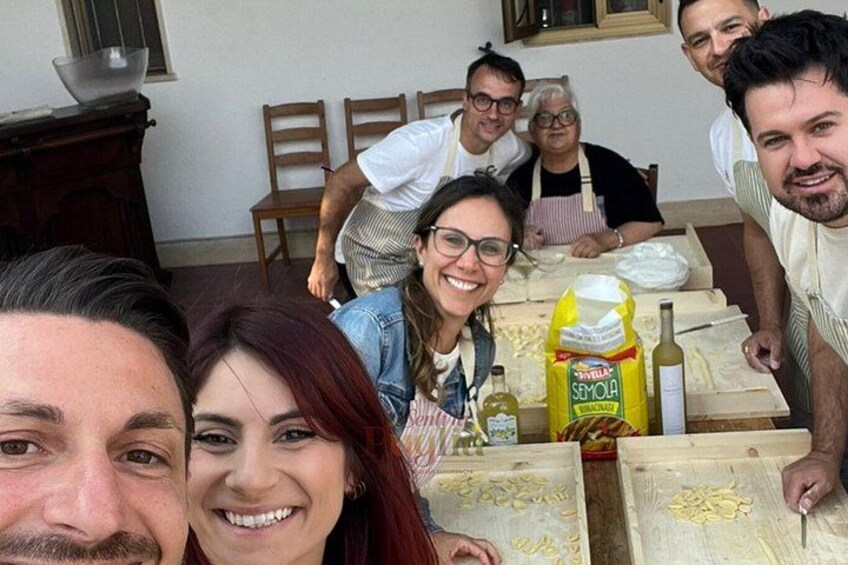 Un gruppo di persone che cucina, con pasta e una bottiglia d'olio d'oliva sul tavolo. 4