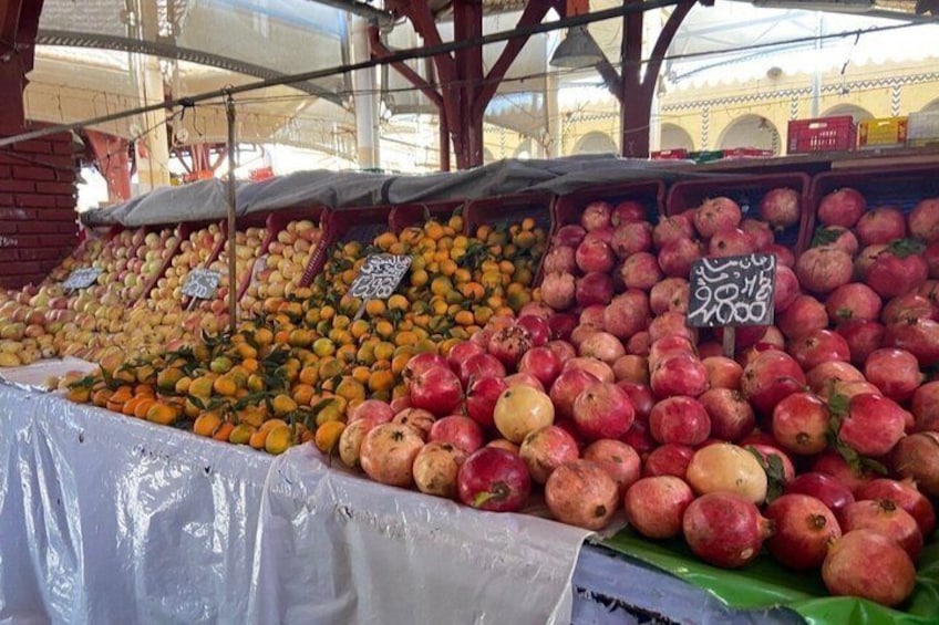 En fruktmarknad där olika sorters frukter, som apelsiner, citroner och granatäpplen, visas upp. 1