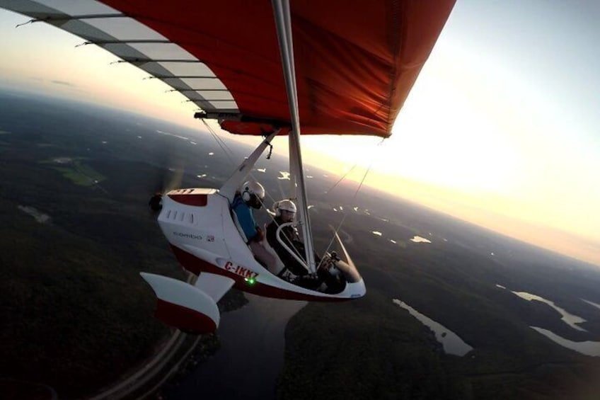 En sejlflyver med rødt trælsejl flyver over et landskab med områder af vand. 3