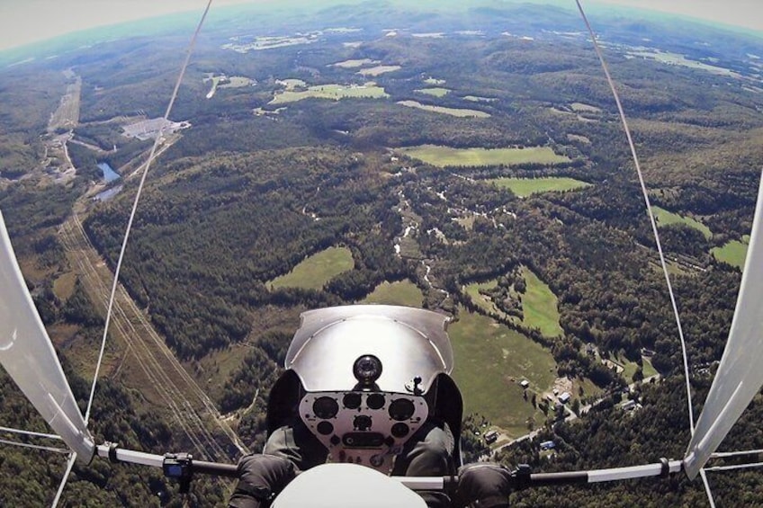 En person i en hangglider med udsigt over et skovlandskab. 5