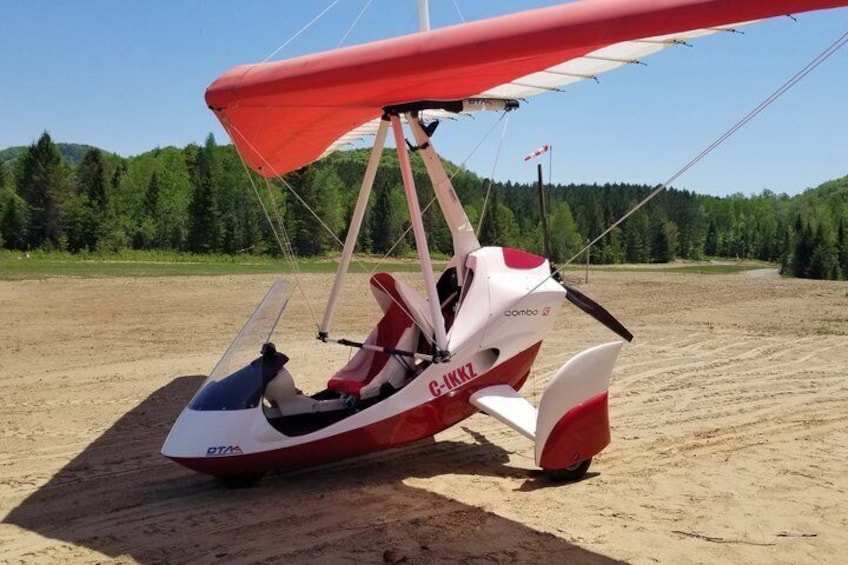 En hangglider med registreringen C-IKMZ på en sandet overflade. 2