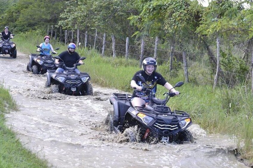A group of people riding ATVs on a muddy path. 1
