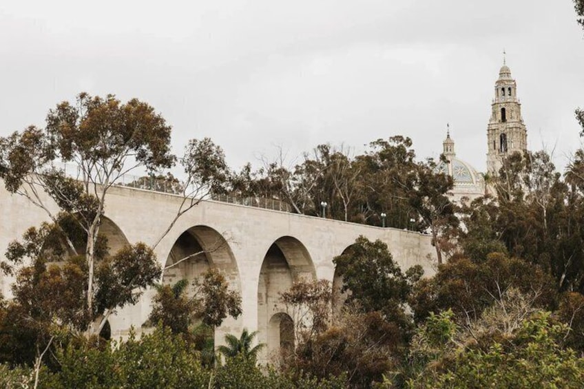 Un ponte in pietra con archi, circondato da alberi e una torre campanaria sullo sfondo. 5