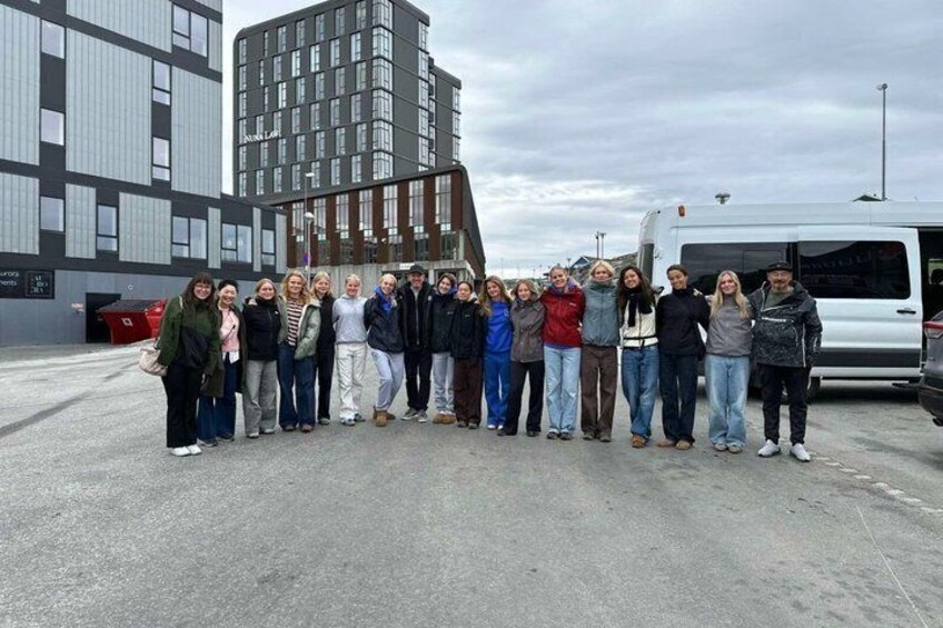 A group of people standing in an open area with modern buildings in the background. 1