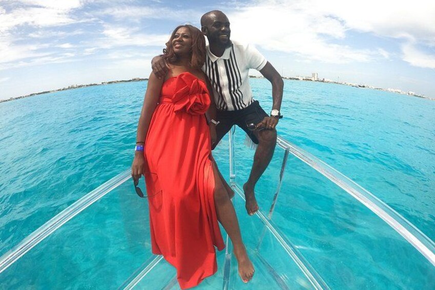 A couple on a boat in clear turquoise waters with a distant shoreline. 5
