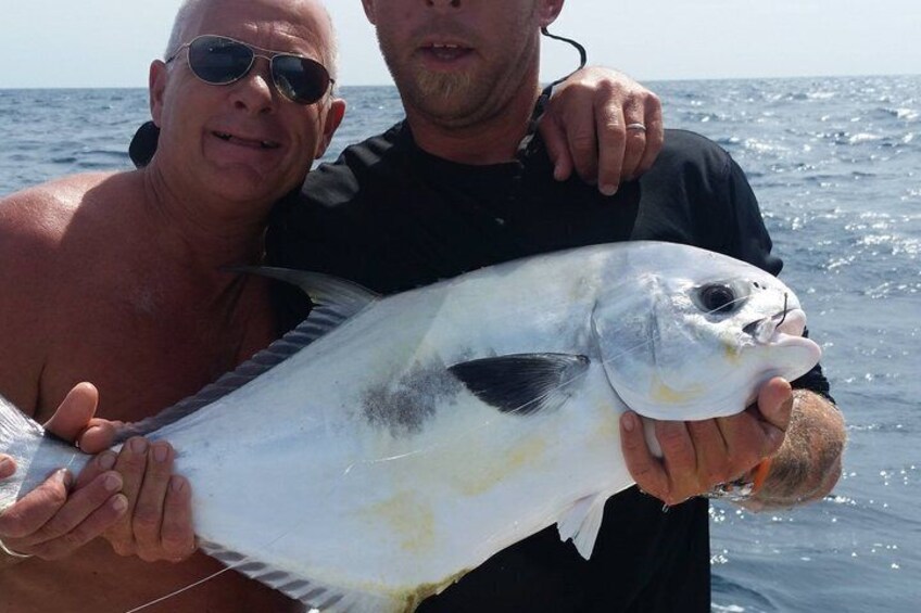 Dos personas sostienen un pez grande, probablemente un pez vela, en un barco en el océano. 3