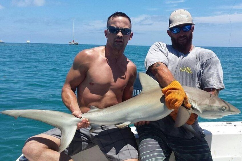 Dos personas en un bote sosteniendo un tiburón grande. 2