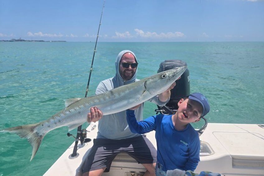 Two people on a boat holding a large fish. 5