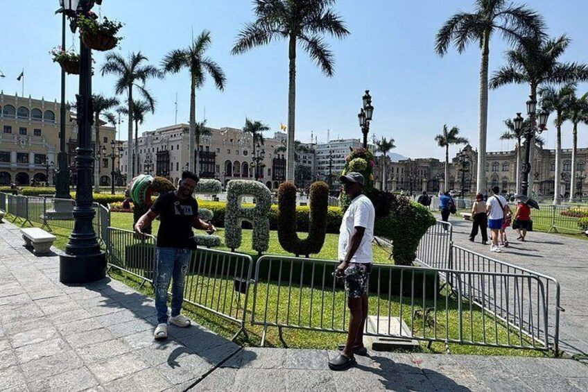Un hombre está de pie cerca de una valla con una gran escultura con forma de letra al fondo. 3
