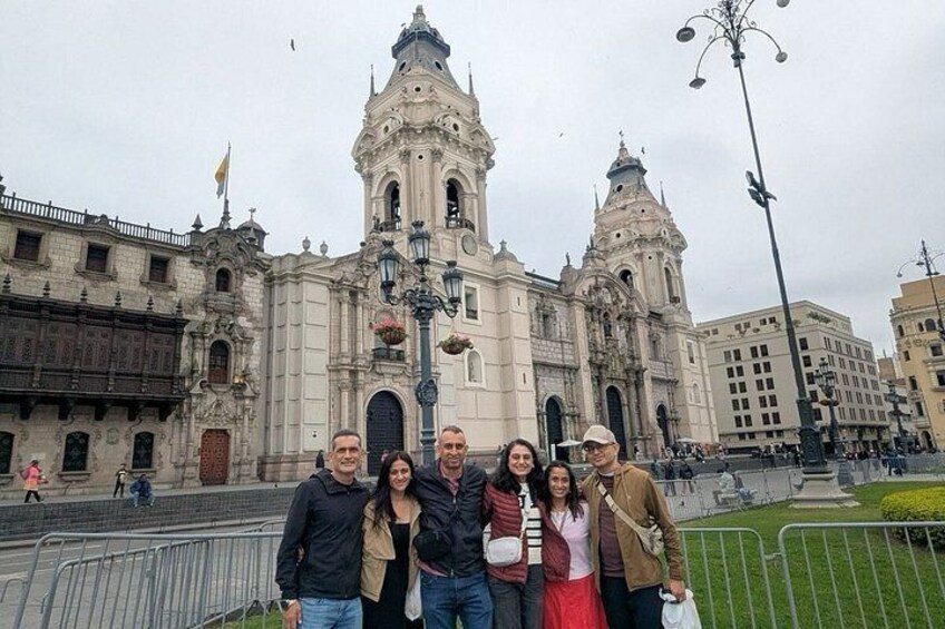 Un grupo de personas frente a un edificio histórico con dos torres y una gran cúpula central. 4
