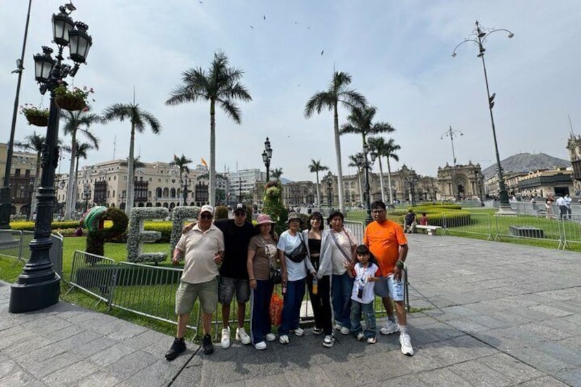 A group of people posing in a public square with palm trees and historic buildings in the background. 1
