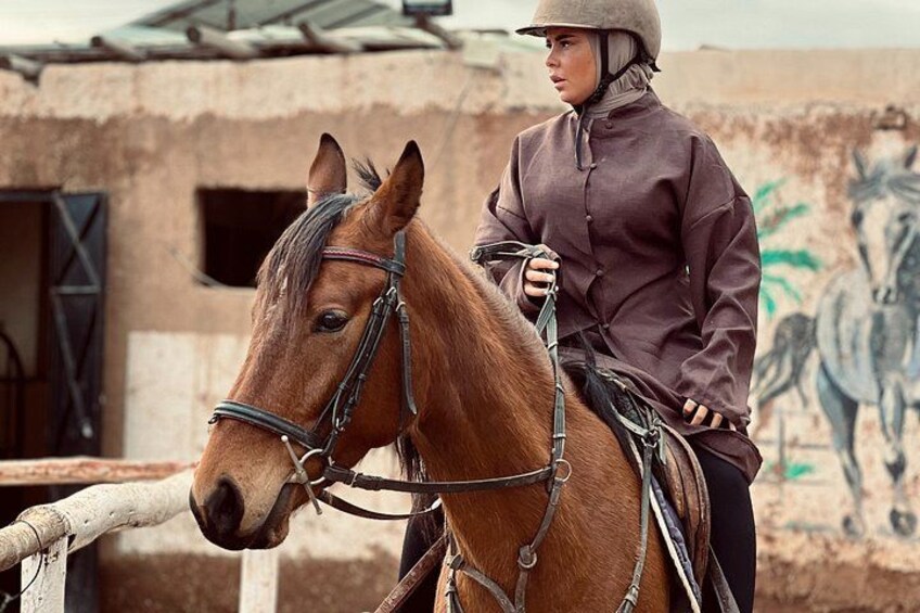Eine Person reitet auf einem Pferd vor einem rustikalen Gebäude mit Wandgemälde. 2