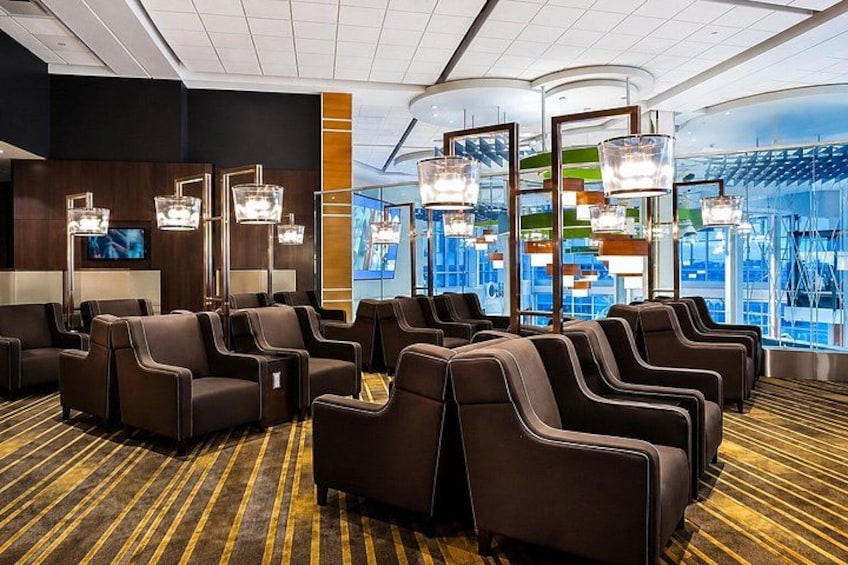 Een hotel lobby met rijen lederen stoelen, een groot televisiescherm en moderne verlichtingsarmaturen. 3