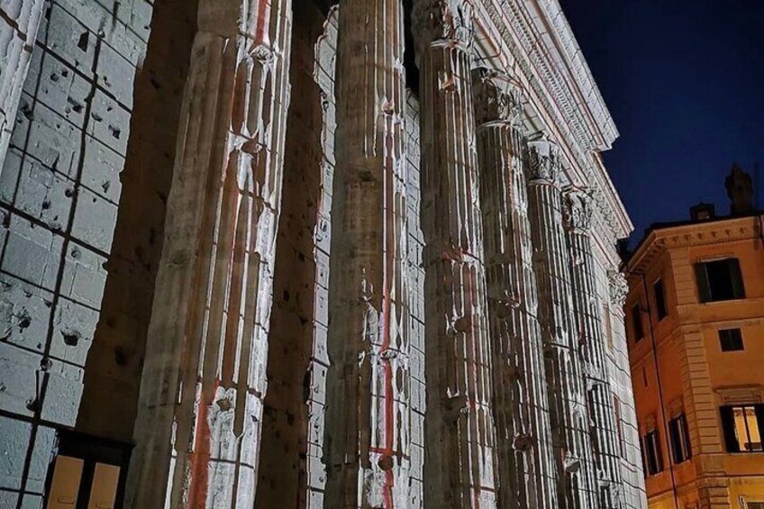 Een historisch gebouw met klassieke zuilen en een gevel met zichtbare slijtage en reparaties. 4