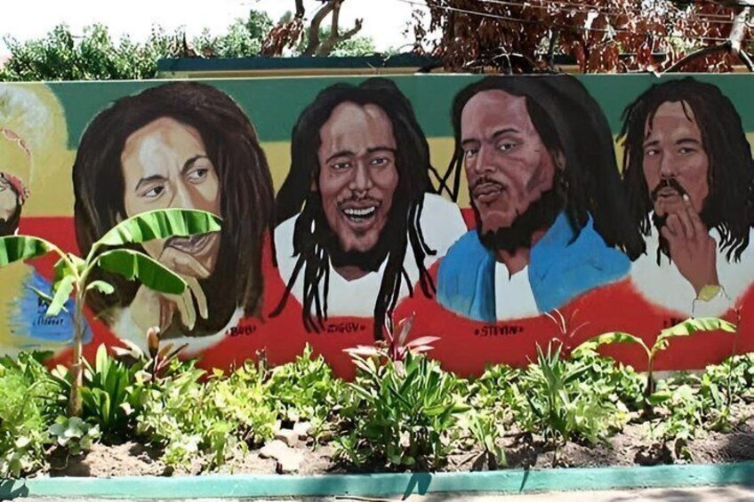A mural with three figures, plants, and a blue painted border. 1