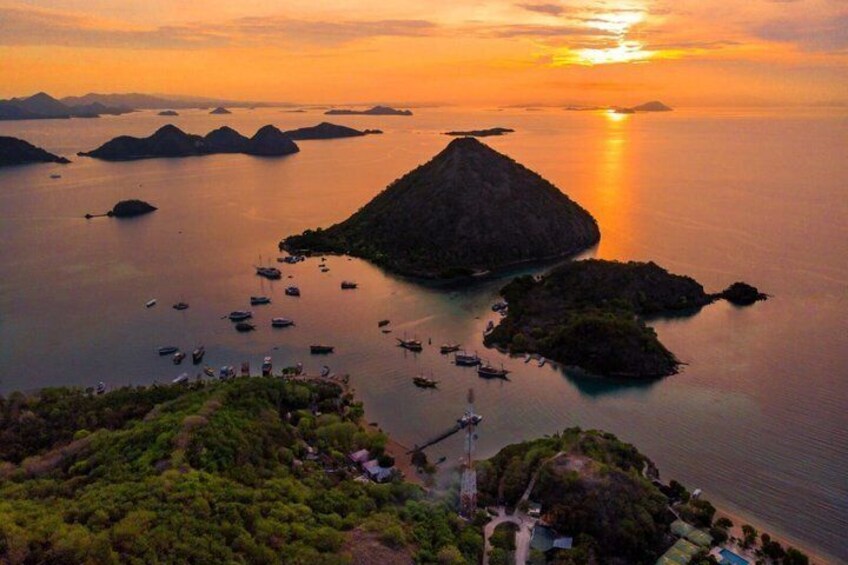 A coastal landscape with a prominent hill, several small islands, and numerous boats in the water. 5