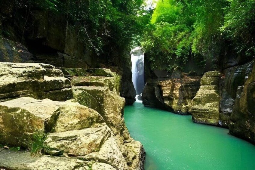 A waterfall cascading through a rocky gorge with green water. 2