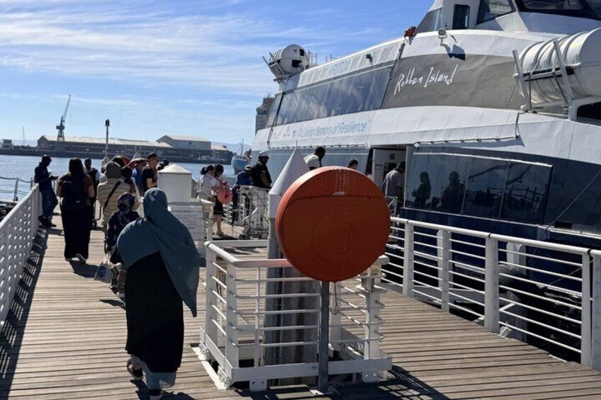 En båt med namnet ”Rothen Island” låg förtöjd vid en brygga, och på bryggan gick folk omkring. En stor, orange livboj var synlig. 2