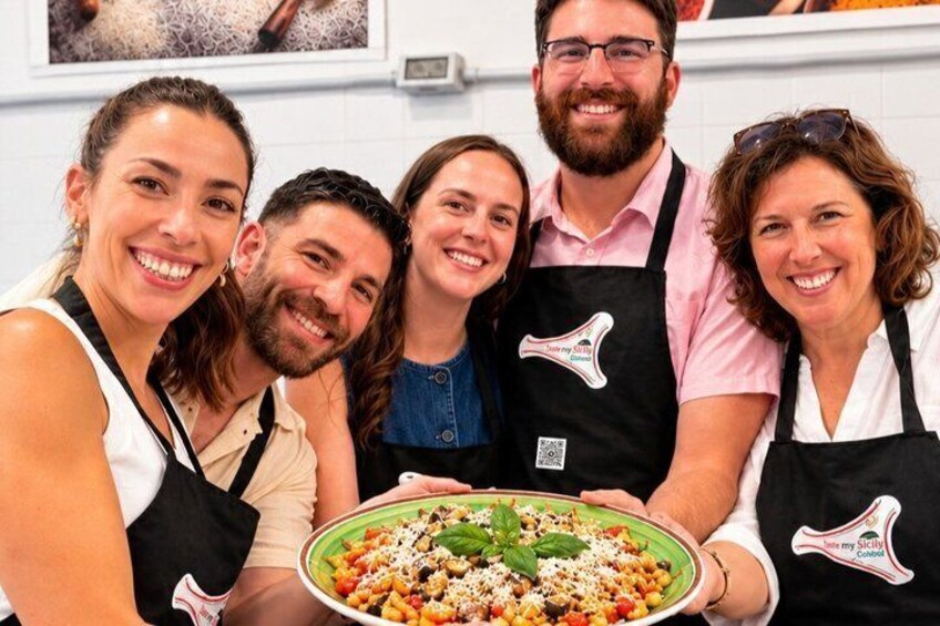 Eine Gruppe von Personen mit Schürzen, die eine große Portion Essen halten. 1