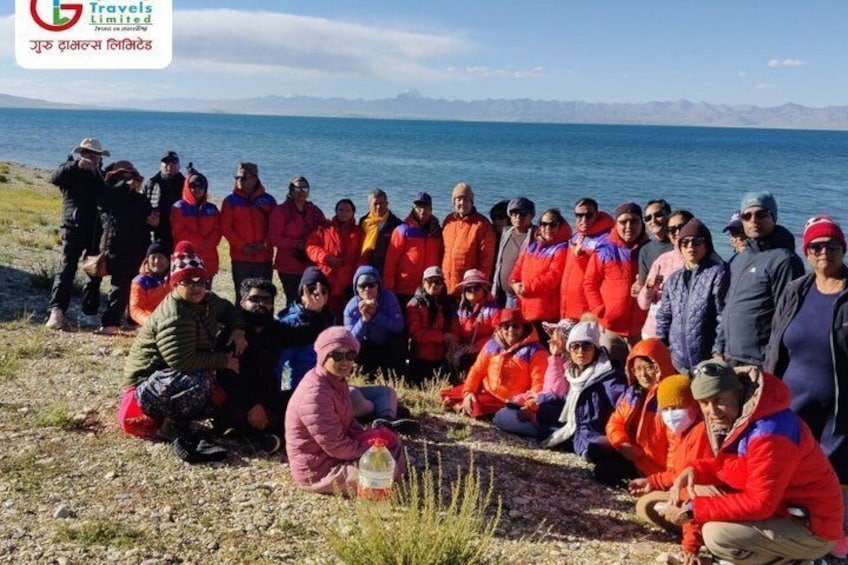 A group of people outdoors near a body of water with mountains in the background. 2