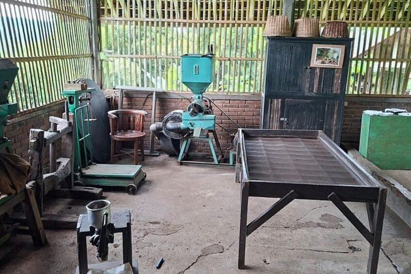 A rustic outdoor setting with a green metal table, a wooden chair, a green machine, and a brick wall. 4