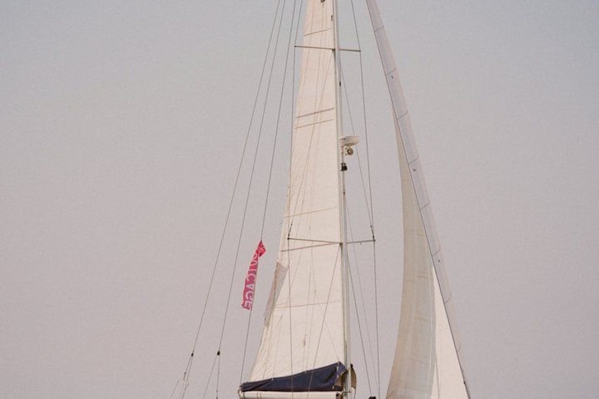 A sailboat's mast with rigging and a red banner. 1